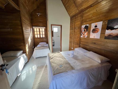 two beds in a room with wooden walls at Pousada Canastra Sul in Delfinópolis