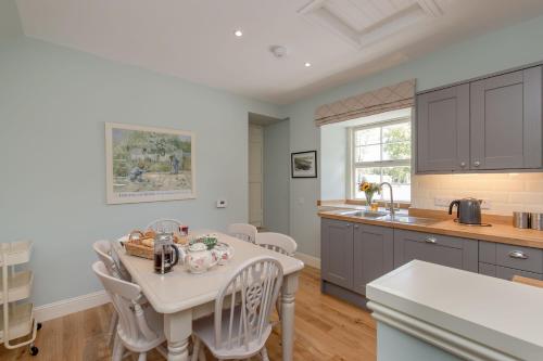a kitchen with a white table and chairs and a counter at Home Farm Cottage in Stranraer