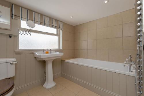 baño con lavabo, bañera y ventana en Home Farm Cottage, en Stranraer