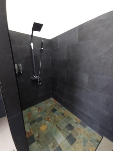a bathroom with a shower with black tiles at Villa MATOANUI in Tevaitoa