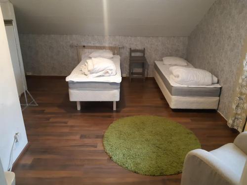 a room with two beds and a green rug at Omakotitalo ykspihlajassa 110m2 in Kokkola