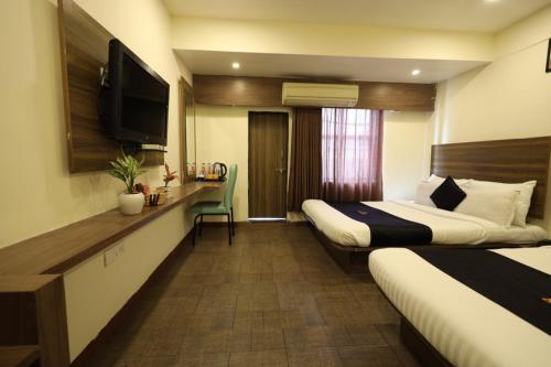 a hotel room with two beds and a flat screen tv at Saish Hotel Shirdi in Shirdi