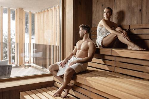 a man and a woman sitting in a sauna at Sporthotel Obereggen in Obereggen