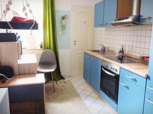 een keuken met blauwe kasten, een wastafel en een fornuis bij Stuckverzierte, zentrumsnahe Wohnung im Süden in Leipzig