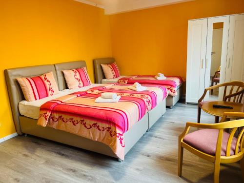 two beds in a room with yellow walls at M&M Hotel - Wilhelmsburg in Hamburg