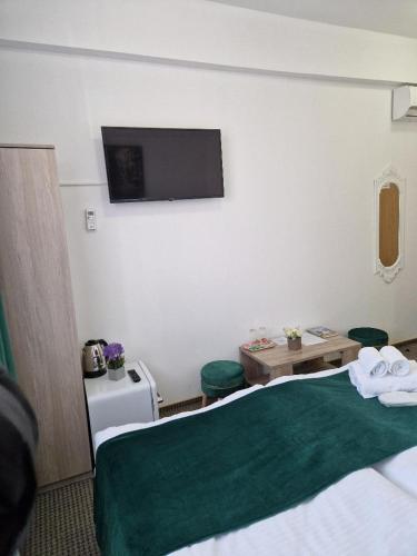 a hotel room with a bed and a flat screen tv at ANTIK HOUSE in Cornu de Jos