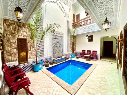 a swimming pool in a large room with red chairs at Riad Nouhal in Marrakech