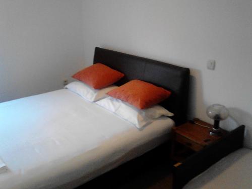 a bedroom with a bed with two orange pillows on it at Mediteraneo Apartments in Budva