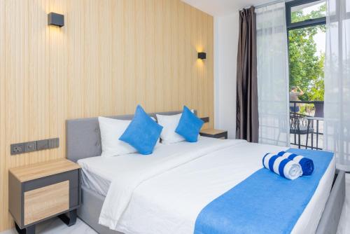 a bedroom with a large white bed with blue pillows at Atoll Residence Dhangethi in Dhangethi