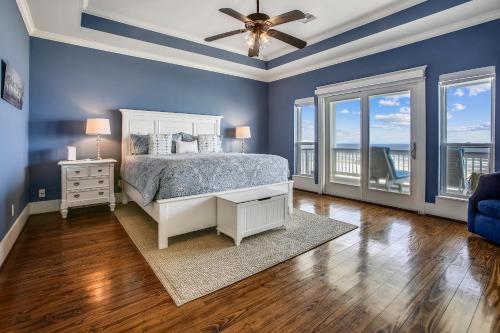 - une chambre avec des murs bleus et un lit avec un ventilateur de plafond dans l'établissement Seaside Sanctuary, à Galveston