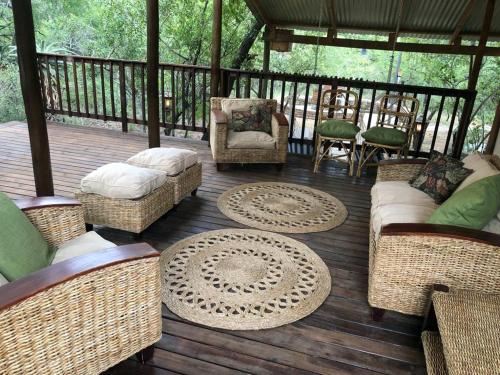 a screened in porch with wicker chairs and furniture on a deck at Pheasant's Crest in Marloth Park