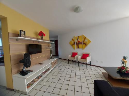 uma sala de estar com televisão e piso em azulejo em Apartamento na praia de Jatiuca em Maceió