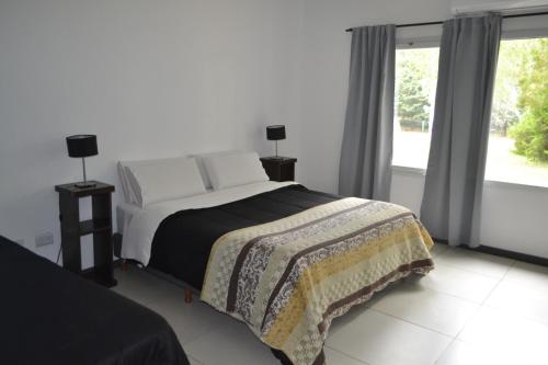 a bedroom with a bed and a large window at VILLAGE PARK in Tandil