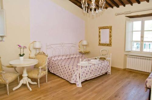 a room with a bed, chair, table and a lamp at B&B Anfiteatro in Lucca