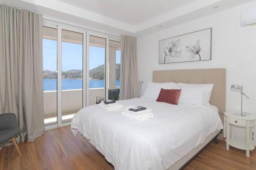 a bedroom with a white bed and a large window at Seaside Apartment M Zaton 5 - Sea View & Parking in Zaton