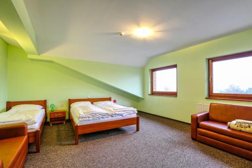a room with two beds and a couch in it at Hotel Tenis in Chrząstowice