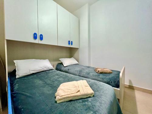 2 camas en una habitación con armarios blancos en Casa Riva Mare, en Riva Ligure