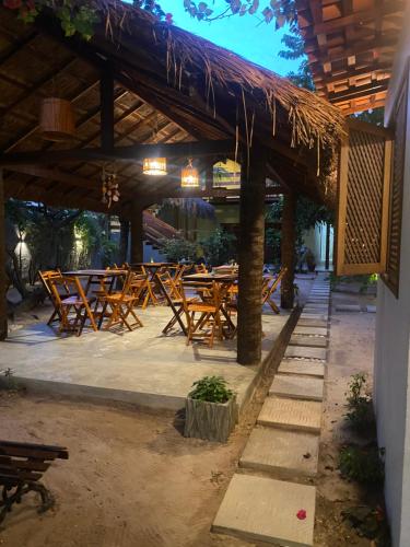 a group of wooden tables and chairs under a roof at Pousada Águas de Tamandaré in Tamandaré