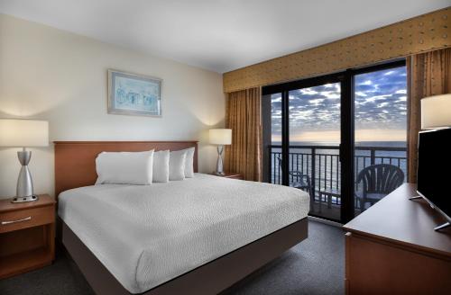 Habitación de hotel con cama y balcón en Beach Cove Resort en Myrtle Beach