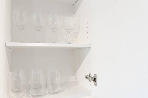 a shelf filled with glasses on top of a sink at Modern & Stylish 1-Bedroom Unit in Edmonton