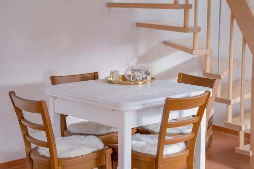 a white table with four chairs and a staircase at Stilvolles kleines Ferienhaus mit Garten 