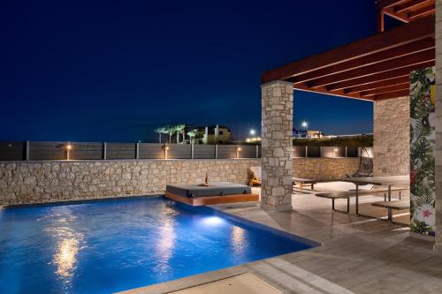 a swimming pool at night with a table and chairs at Southrock Villas in Lachania