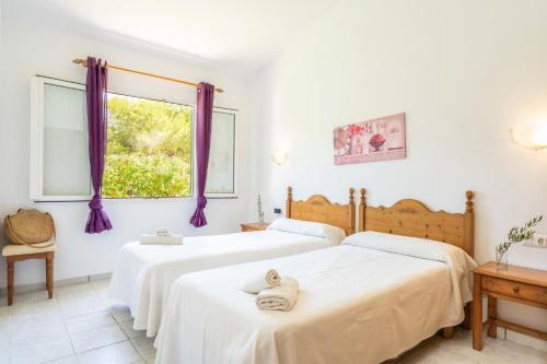 two beds in a white room with purple curtains at Villa Luna by Villa Plus in Cala'n Bosch