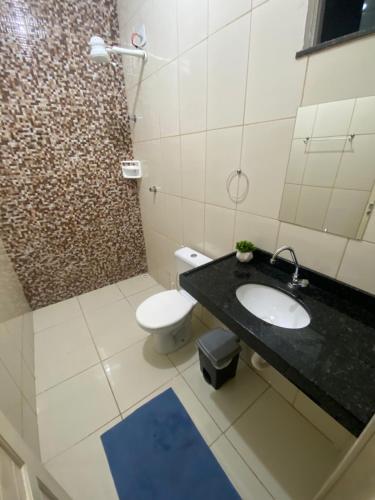 uma casa de banho com um WC branco e um lavatório. em Apuama Hostel em Ubajara