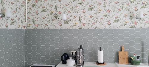 a kitchen with a tiled wall with floral wallpaper at Les Colibris - Standing et Jardin - 3 étoiles in Cluses