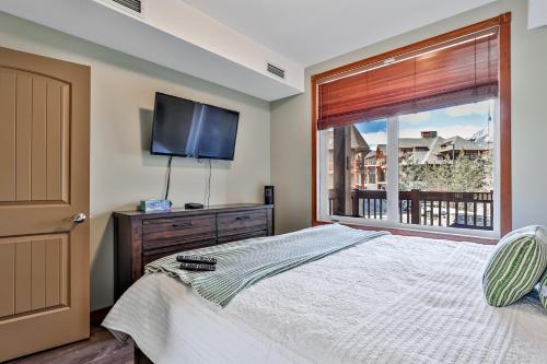 1 dormitorio con 1 cama, TV y ventana en Fenwick Vacation Rentals Inviting Rocky Mountain HOT TUB in Top Rated Condo, en Canmore