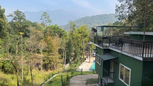 a green building with a balcony and a road at Achapas Garden Villla in Kondotti