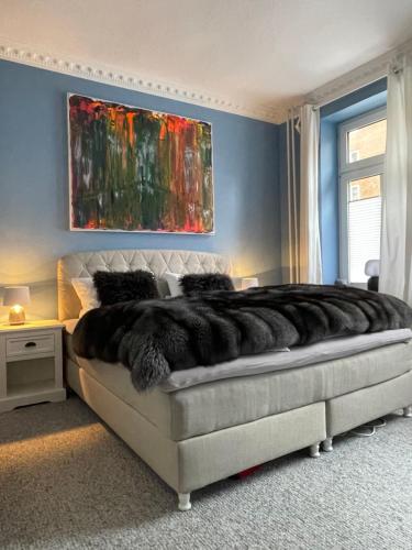 a bedroom with a large bed with a painting on the wall at Luxus Altbaucharme in zentraler Lage in Kiel