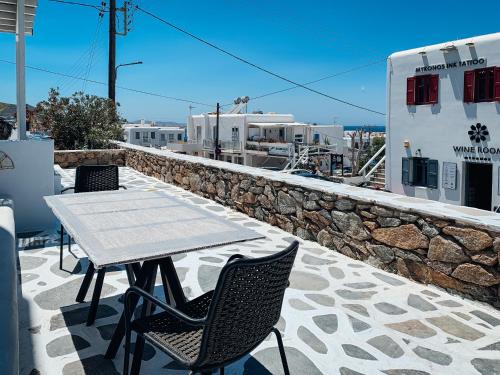 a table and chairs on a patio with a stone wall at Fabrica Sunset Apartments in Megali Ammos