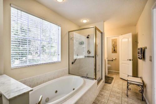 baño con bañera y ducha con ventana en Charming Waldo Getaway Near Lake Santa Fe!, en Waldo