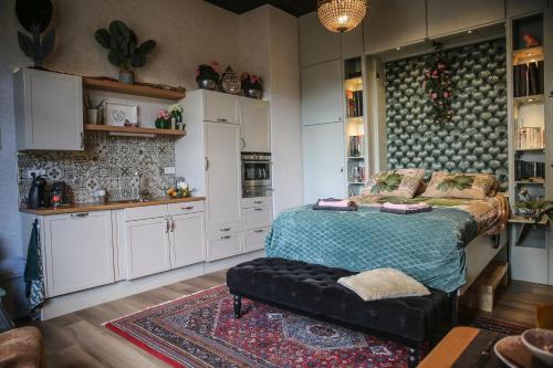 a bedroom with a bed and a kitchen with white cabinets at B&B de Hartewens in Zuidland