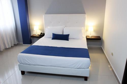 a bedroom with a large white bed with a blue pillow at Eslait Hotel & Apartamentos in Barranquilla