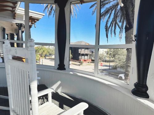a porch with a white rocking chair and windows at The Mansion on 17th, formerly Schaefer Haus in Galveston
