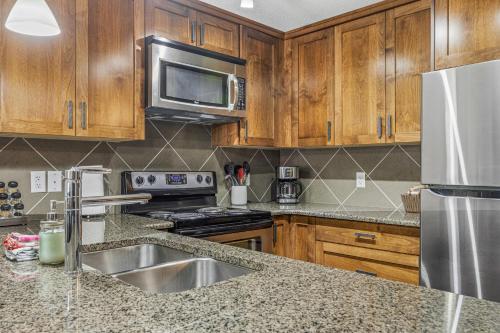 a kitchen with wooden cabinets and a stainless steel appliances at Stoneridge Mountain Resort Condo managed by Little Sister Getaways in Canmore