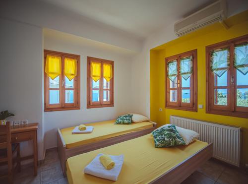 two beds in a room with yellow walls and windows at Lemon House for big family in Damouchari - Delicious Houses in Damouchari