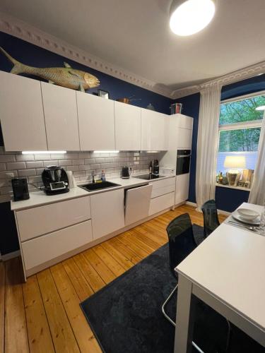 a kitchen with white cabinets and a blue wall at Luxus Altbaucharme in zentraler Lage in Kiel