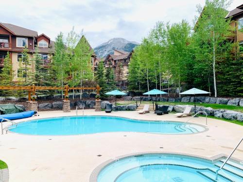 einen Pool im Garten mit Stühlen und Sonnenschirmen in der Unterkunft Stoneridge Mountain Resort Condo hosted by Fenwick Vacation Rentals in Canmore