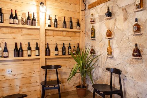 a bar with two stools and bottles of wine at Burzan Bungalovi in Podgorica