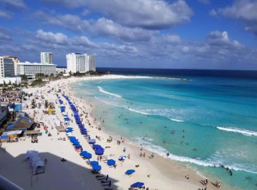 een strand met mensen en parasols en de oceaan bij Beach Front Renewed Apartment in Cancun