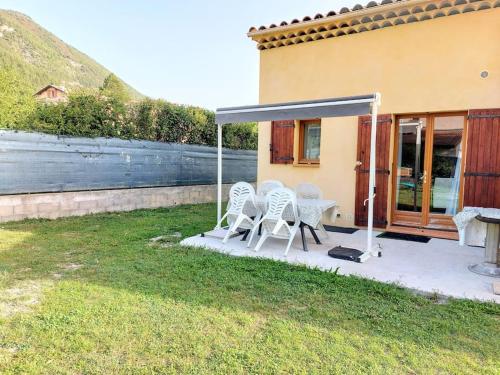 um pátio com duas cadeiras e um dossel ao lado de uma casa em Rez de jardin dans quartier calme et ensoleillé em Saint-André-les-Alpes