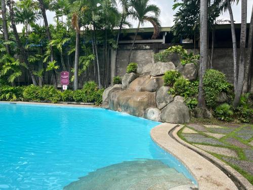 een zwembad in een resort met palmbomen bij The Cozy Place Condo in Pasig Phil in Manilla