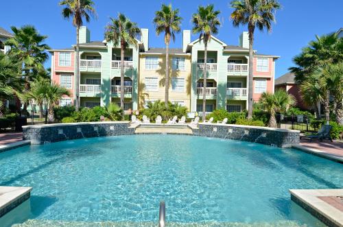 a swimming pool in front of a building with palm trees at Dawn 625 in Galveston