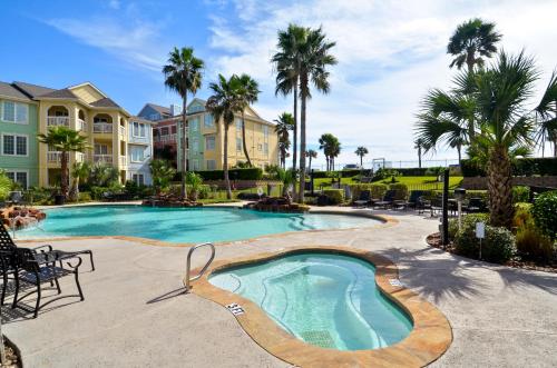 a swimming pool with palm trees and condos at Dawn 625 in Galveston