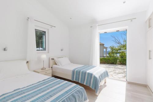 2 Betten in einem weißen Zimmer mit Fenster in der Unterkunft Villa Ester by Villa Plus in Kalámi