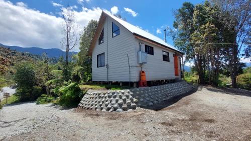 a house with a pile of rocks in front of it at Cabañas & Habitaciones Del Alto in Hornopiren