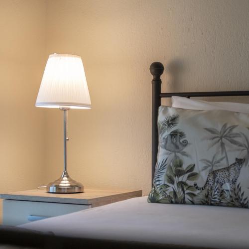 a lamp sitting on a night stand next to a bed at Evdokia's Apartments and Rooms in Neos Marmaras